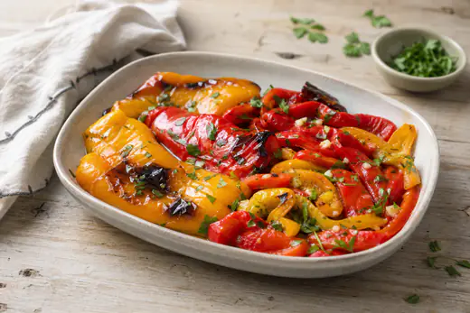 Pimentos vermelhos e amarelos assados, com a pele ligeiramente queimada, cortados em tiras e temperados com azeite e alho