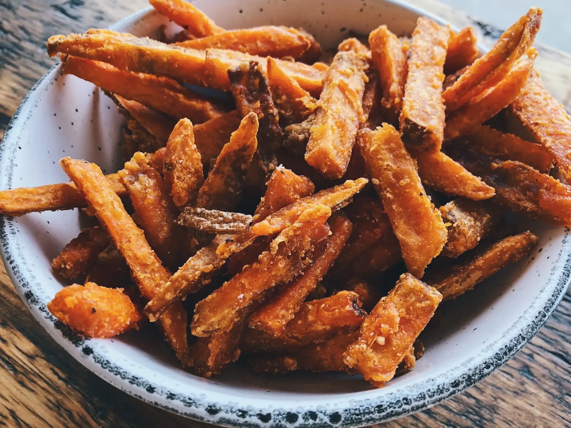 Batatas-doces fritas na airfryer crocantes e douradas servidas em um prato.